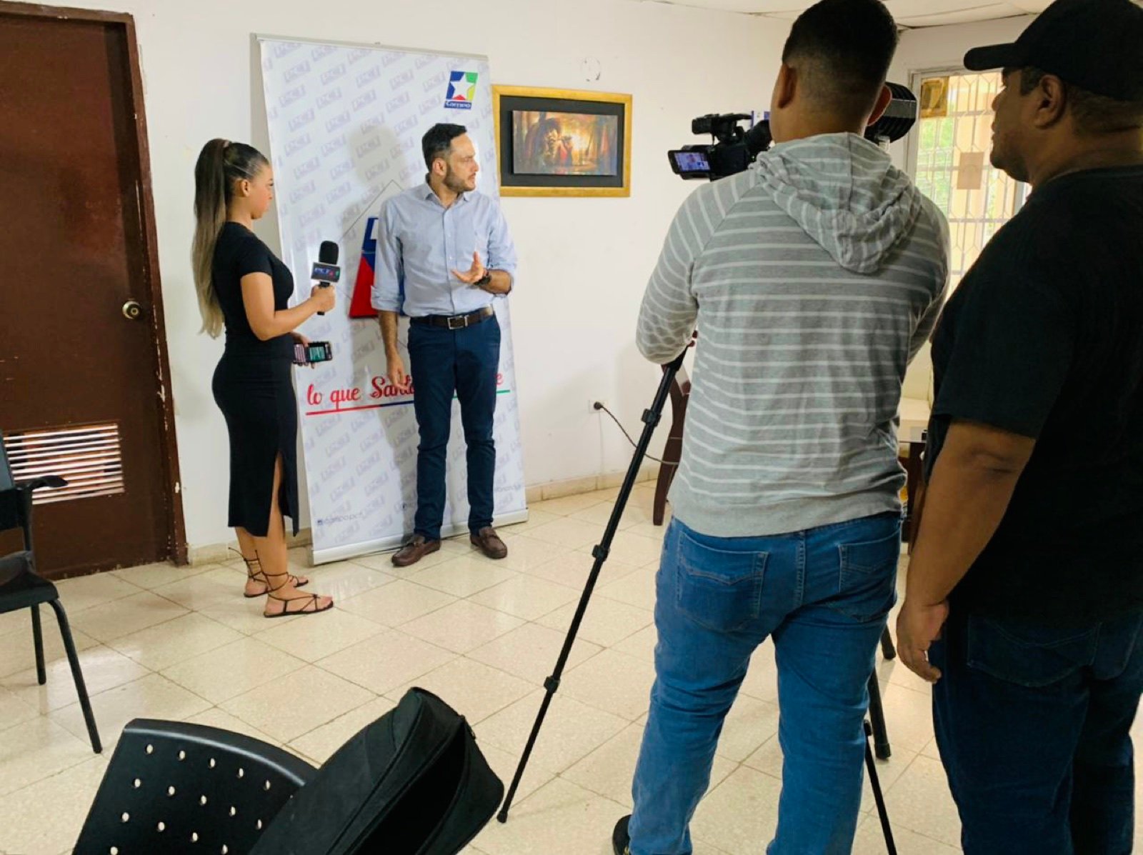 Madel Cuza entrevistando frente a una cámara de televisión
